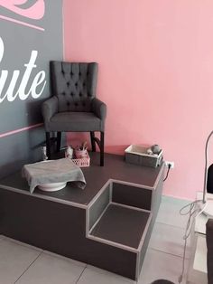 a hair salon with pink walls and grey chairs in the corner, one chair is up against the wall