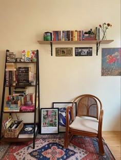 a room with a chair, bookshelf and pictures on the wall above it