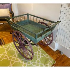 a green wagon sitting on top of a wooden floor next to a white wall and rug