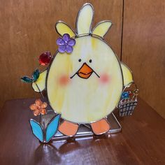 a glass bird sitting on top of a wooden table next to a basket and flowers