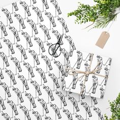 two wrapping paper with scissors on them next to some green plants and a white background