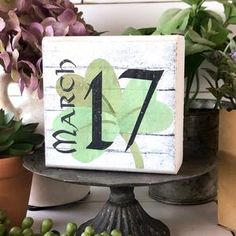 a wooden sign with the number seven on it next to potted plants and flowers