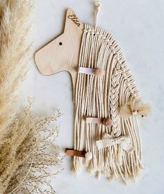 a wooden dog ornament next to some dried grass and dry plants on a white surface