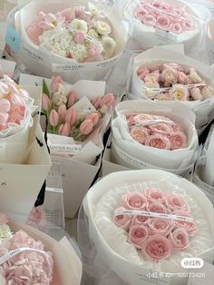 many different types of flowers in white boxes on display at a flower shop, some are pink and one is white