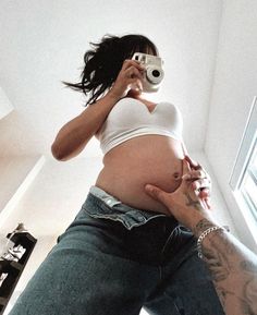 a pregnant woman taking a selfie with her camera