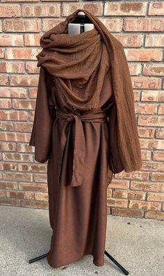 a brown robe is on display in front of a brick wall