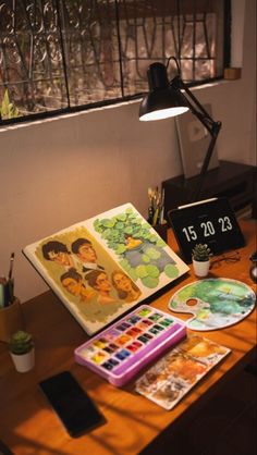 Minimalist desktop art studio Artist's workspace with sketchbook, watercolor paints, and digital clock on wooden desk. | Sky Rye Design