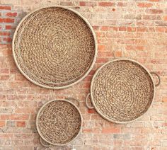 three round woven baskets sitting on top of a brick wall