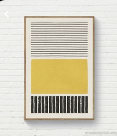 a yellow and black painting hanging on a white brick wall