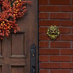 the door is brown and there are red berries in front of it on the brick wall