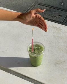 a hand holding a straw over a green drink