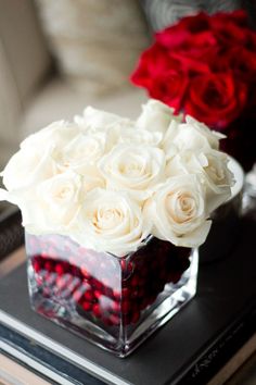 a vase with white roses and red berries in it on a tabletop next to an instagram post