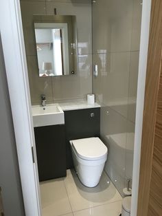 a white toilet sitting inside of a bathroom next to a sink under a large mirror