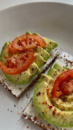 two slices of bread with tomatoes and avocado on them