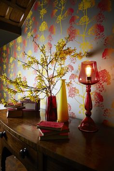 two vases and a lamp on a table in front of a floral wallpaper