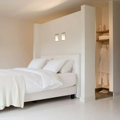 a white bed sitting inside of a bedroom next to a closet