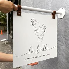 a person holding up a sign that reads la belle studio beaute by leti