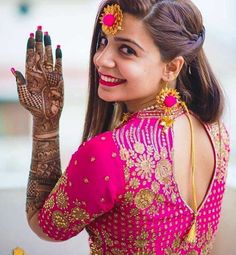 a woman in a pink dress holding her hands up to show the henna on her hand