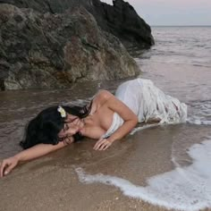 a woman laying on top of a sandy beach next to the ocean