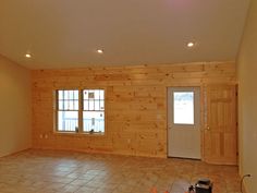 an empty room with wooden walls and tile floor