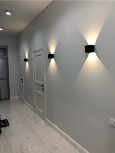 three lights are on the wall in an empty room with white walls and marble flooring