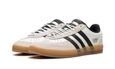 The Bad Bunny x adidas Gazelle Indoor “Off White” is a collaboration on the retro indoor soccer style by the ultra-popular international recording artist.  Bad Bunny and adidas’s partnership began with a bang with the debut of the adidas Forum Buckle Low in 2021.  Since then, the pair has released several high-profile sneakers, including this Gazelle Indoor in versatile “Off White. ” The upper has an Off White leather design with grey hairy suede overlays on the toe and heel.  Oversized black leather Three Stripes branding appears on either side of the shoe, while “adidas” “Benito” stamps can be seen on the lateral side of the mid-panel.  White rope-style laces are layered over the black tongue.  A semi-translucent Gum rubber sole completes the look. Soccer Style, Adidas Outfit Shoes, Adidas Gazelle Indoor, Adidas Three Stripes, Yeezy 500, Adidas Forum, Indoor Soccer, Off White Shoes, Yeezy 700