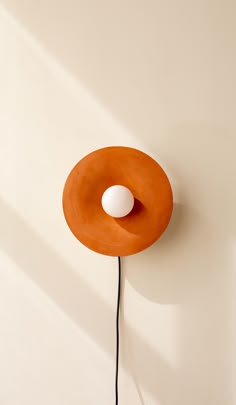 an orange object with a white ball on it's head hanging from a wall