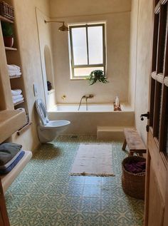 a bath room with a toilet a sink and a bath tub next to a window