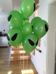 a bunch of green balloons with black eyes on them sitting in front of a door