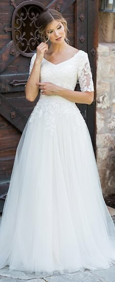 a woman in a white wedding dress posing for the camera with her hand on her hip