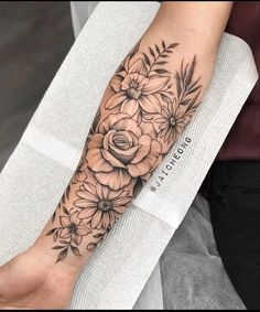 a black and white flower tattoo on the left arm, with flowers in it's center