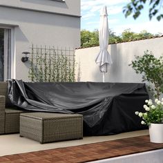 an outdoor patio covered with a black tarp and some flowers on the side of it