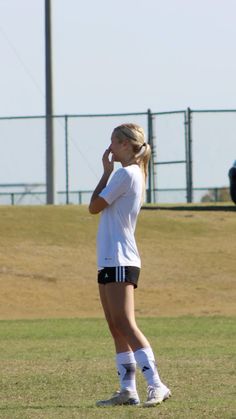 a young woman standing on top of a field holding a soccer ball in her hand