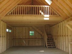 the inside of a building with wooden walls and stairs leading up to an upstairs loft