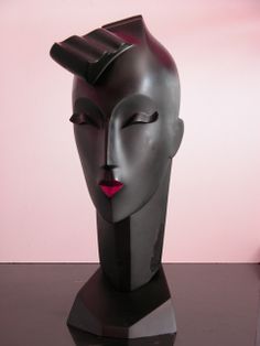 a sculpture of a woman's head with red lips on a black table in front of a pink wall