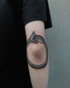 a black and white snake tattoo on the left arm, with a circle around it