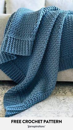 a blue knitted blanket sitting on top of a couch with the text free crochet pattern