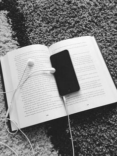 an open book with headphones laying on the ground