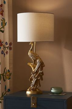 a lamp that is sitting on top of a blue table next to a vase with a bird on it