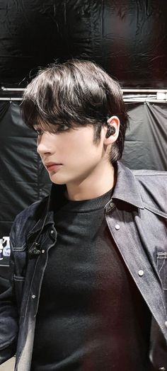 a young man with black hair wearing ear buds