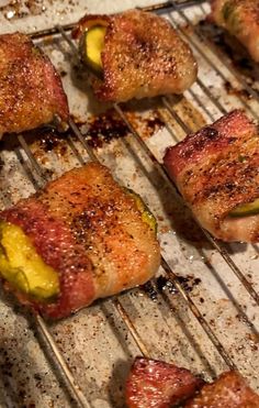 several pieces of meat are being cooked on a grill with peppers and zucchini