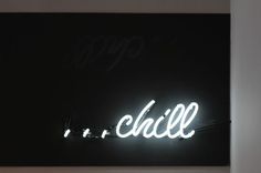 a neon sign that says chill on the side of a wall in a dark room