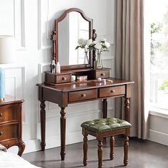 a dressing table with a stool and mirror in a room next to a window,