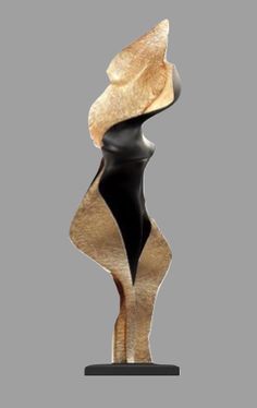 an abstract sculpture on a black base with gold and black accents, against a gray background