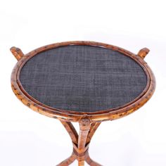 a round wooden table with black fabric on the top and two small circular wood legs