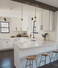 a kitchen with white cabinets and wooden stools