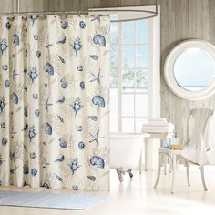 a white bath tub sitting next to a shower curtain covered in blue seashells