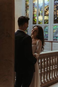 a man and woman standing next to each other in front of a building with stained glass windows