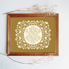 a framed art print with a quote in the center on a white wall next to dried plants