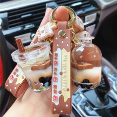 a person holding a keychain in their hand with some food inside it and two jars filled with liquid